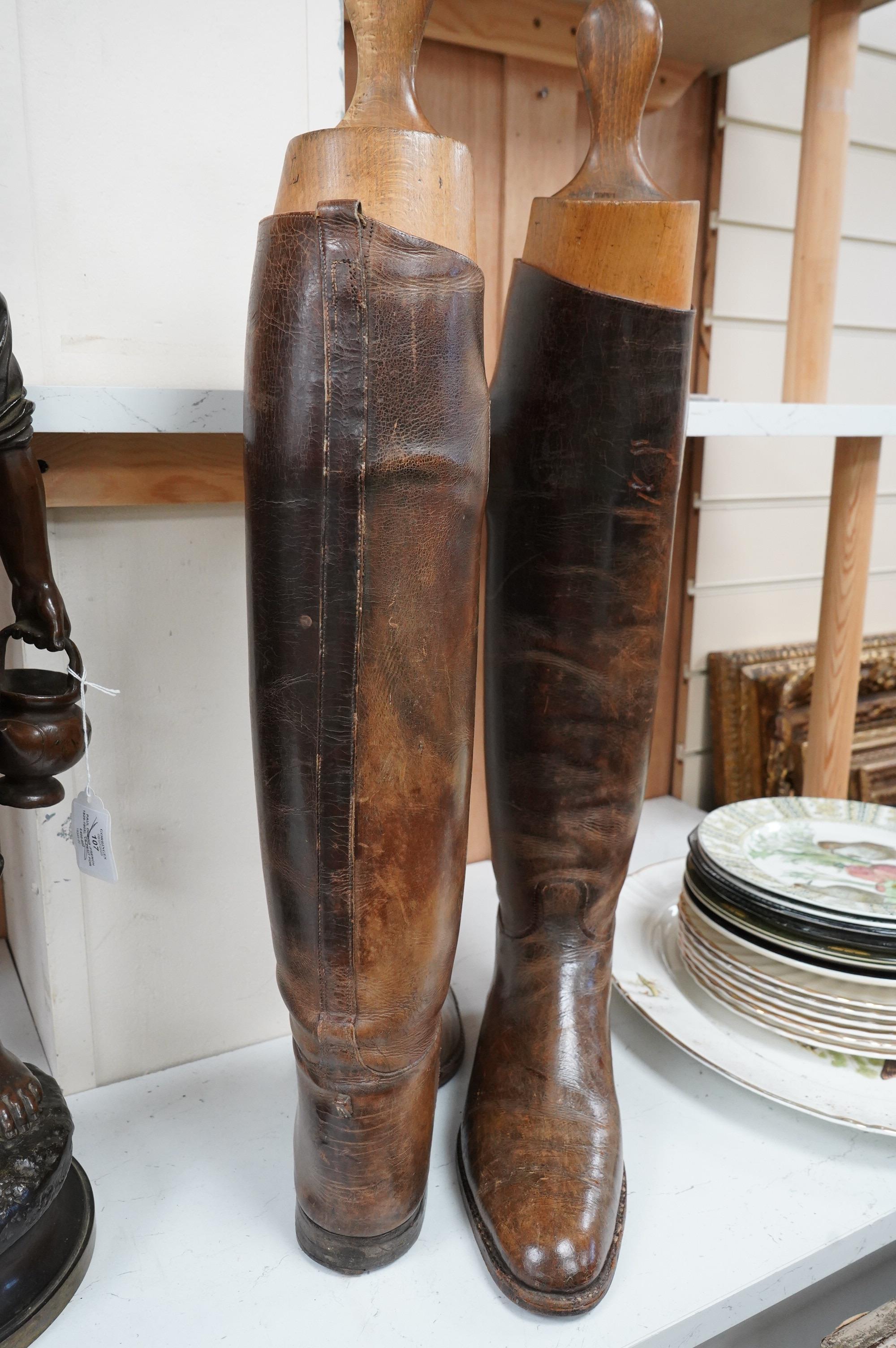 A pair of brown leather riding boots with beech trees